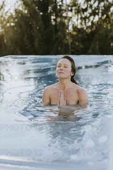 Woman folds her hands while ice bathing in the pool