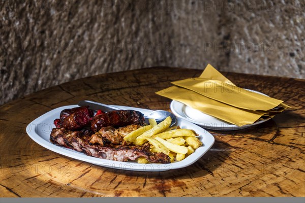 Mixed meat barbecued and served with french fries in restaurant in the cave