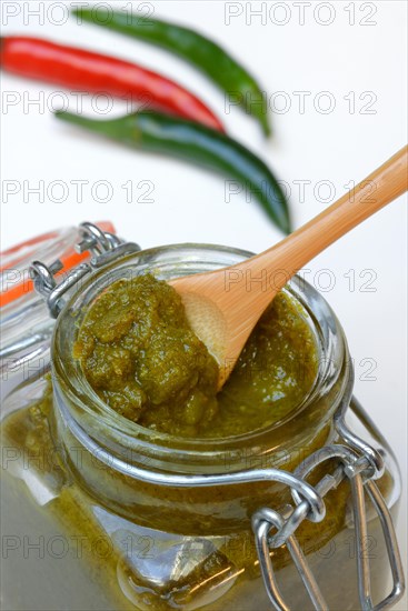 Green Thai curry paste in jar and chillies
