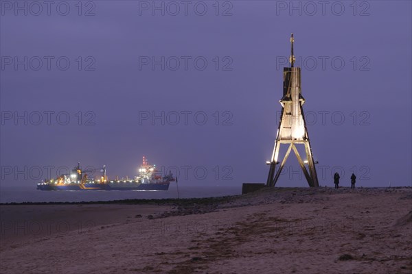 Illuminated Kugelbake and illuminated ship at blue hour