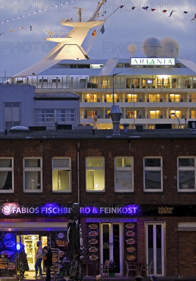 Fish market shops and cruise ship Artania at Hamburg Cruise Center Altona in the evening