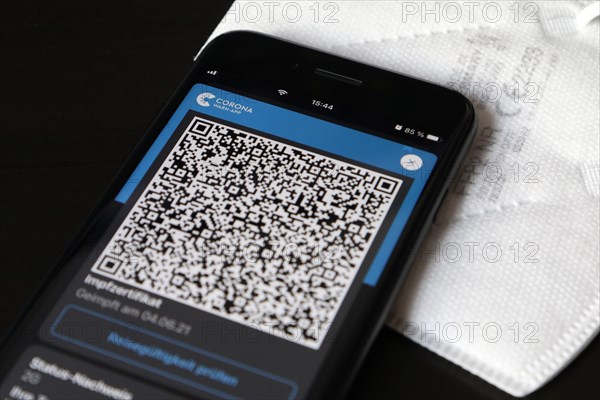 FFP2 mask and iPhone with Corona warning app with QR code for vaccination certificate
