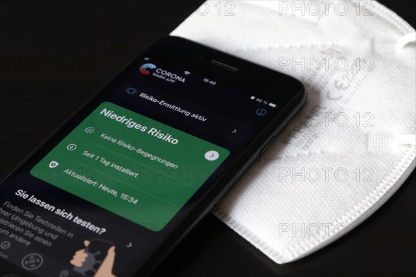 FFP2 mask and iPhone with low-risk Corona warning app