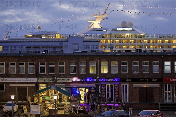 Fish market shops and cruise ship Artania at Hamburg Cruise Center Altona in the evening