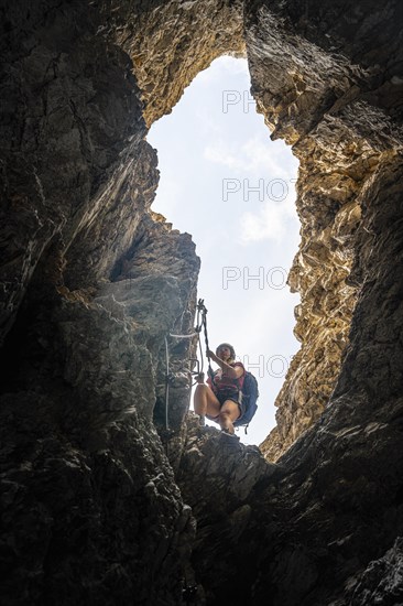 Young woman climbing a steep rock face