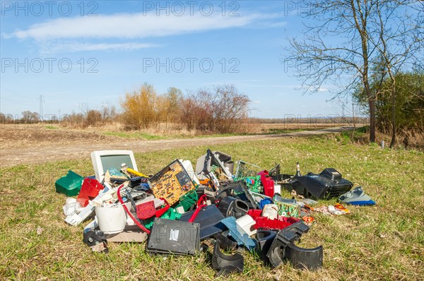 Polluting plastic waste and computer scrap illegally disposed of in a meadow