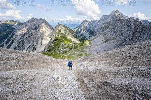 Hiker descends over a boulder field to the Lamsenjochhuette