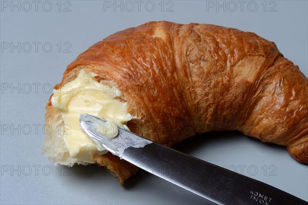 Butter with knife on croissant
