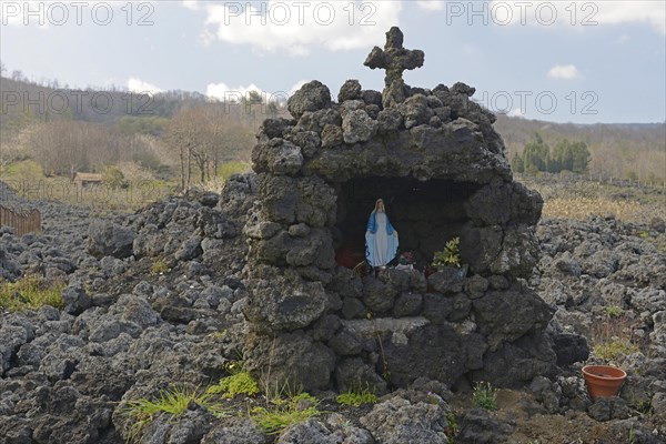Lava rock and statue of the Virgin Mary at the foot of Mount Etna