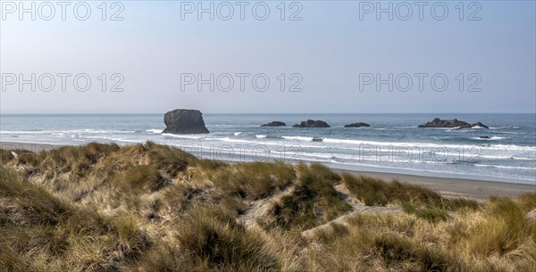 View over sandy beach with dunes and large rocks