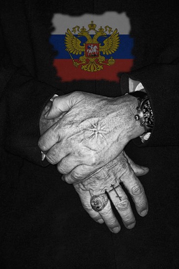 Two crossed hands with Russian tattoos and the Russian coat of arms in the background