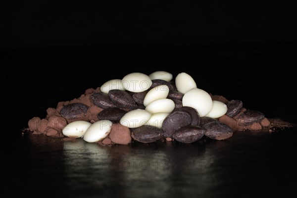 Dark and white couverture chocolate drops lying on cocoa powder