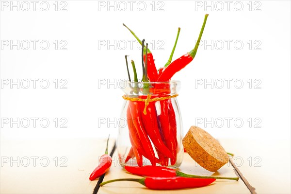 Red chili peppers on a glass jar over white wood rustic table