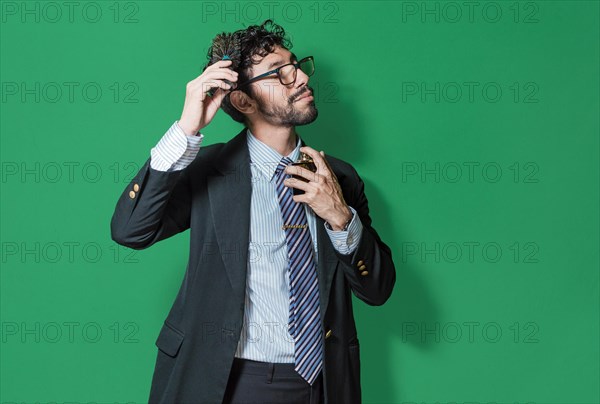 Elegant businessman perfuming himself and combing his hair