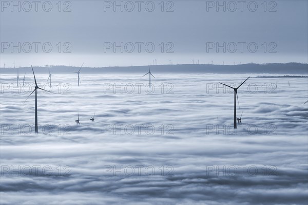 Wind turbines rising from cloud cover