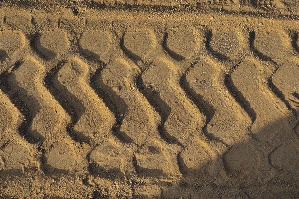 Wide tyre print in the sand from agricultural machine