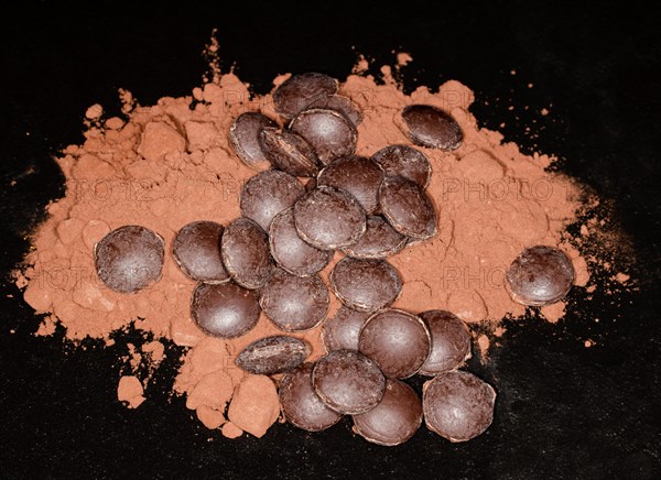Dark couverture chocolate drops lying on cocoa powder