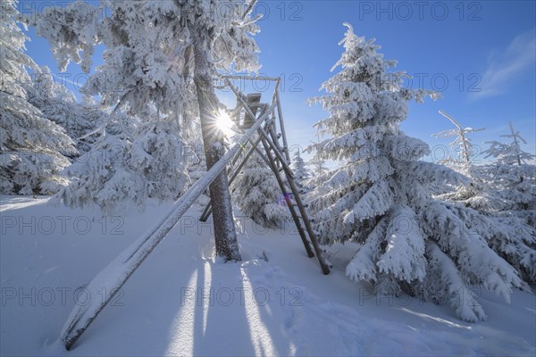Snow covered winter landscape with raised hide and sun