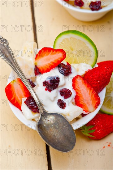 Fruit and yogurt salad healthy breakfast over white wood table