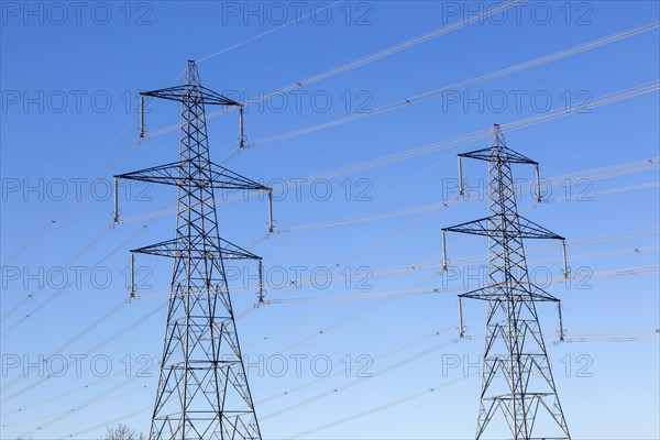 Electrical pylons and high voltage electricity transmission power lines from Sizewell nuclear power station against blue sky