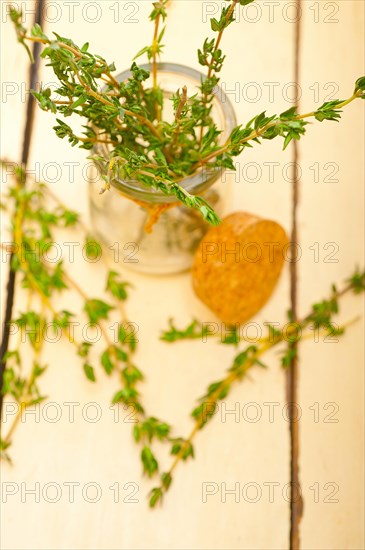 Fresh thyme on a glass jar over a white wood rustic table