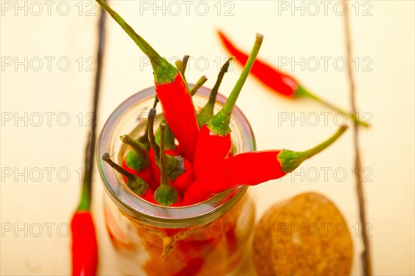 Red chili peppers on a glass jar over white wood rustic table