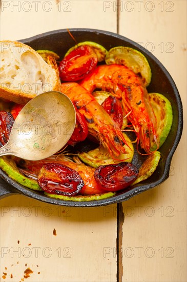Roasted shrimps on cast iron skillet with zucchini and tomatoes