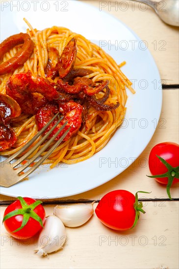 Italian seafood spaghetti pasta on red tomato sauce over white rustic wood table