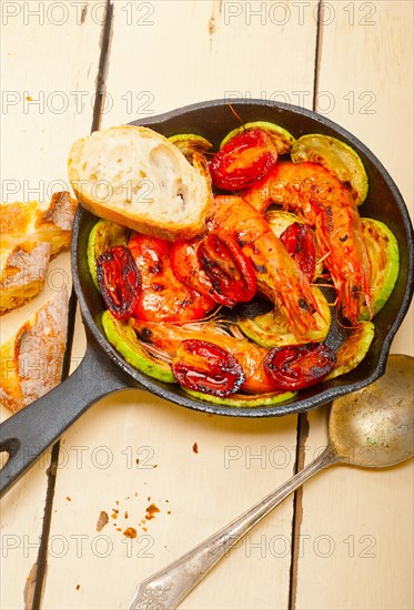 Roasted shrimps on cast iron skillet with zucchini and tomatoes