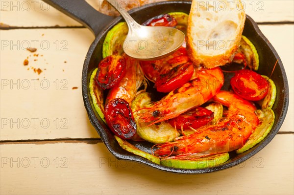 Roasted shrimps on cast iron skillet with zucchini and tomatoes