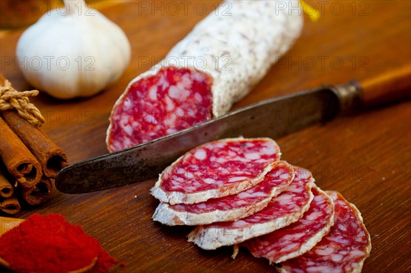 Traditional Italian salame cured sausage sliced on a wood board