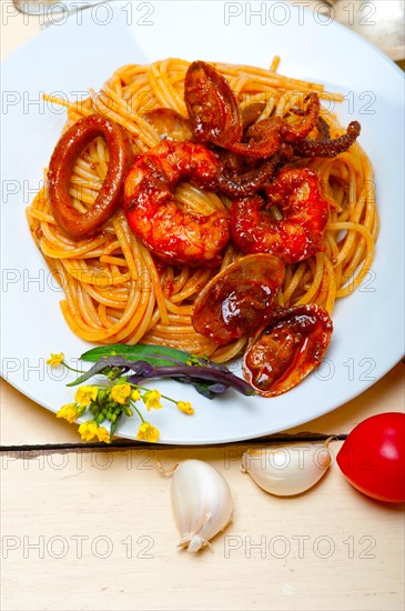 Italian seafood spaghetti pasta on red tomato sauce over white rustic wood table