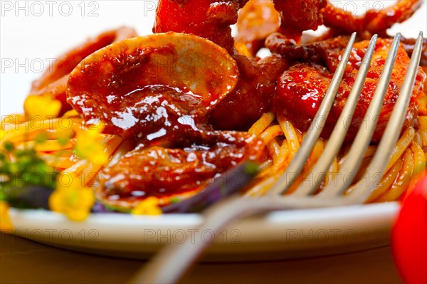 Italian seafood spaghetti pasta on red tomato sauce over white rustic wood table