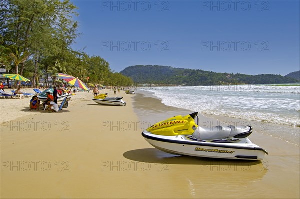 Patong Beach with umbrellas and tourists by the sea in Thailand