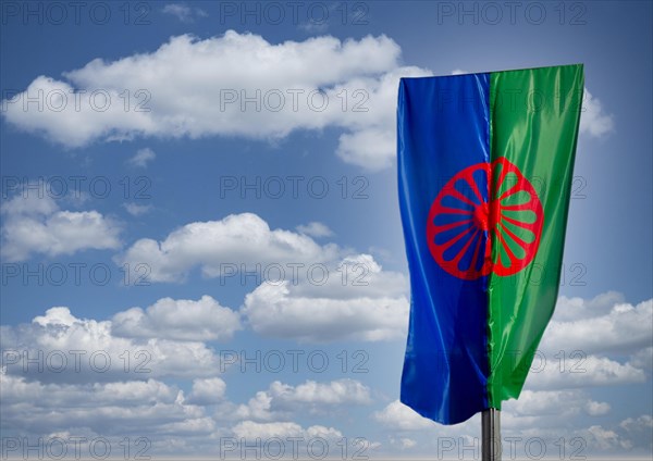 Eine Roma und Sintiflagge weht im Wind mit Wolken als Hintergrund