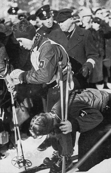 The sister helps. . ! It is Christl Cranz here unstrapping the boards for her brother Rudi after his dashing downhill run
