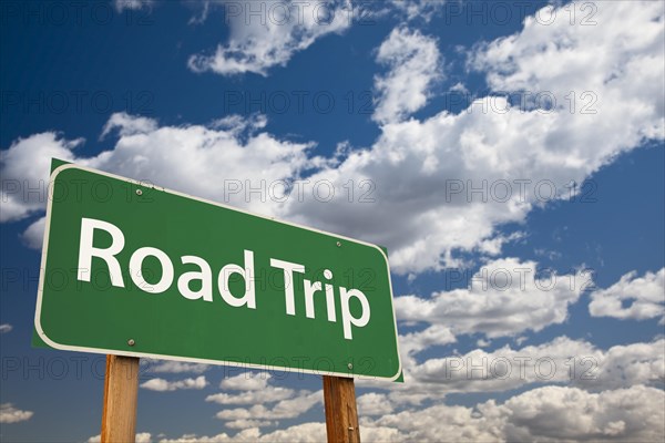 Road trip green road sign with dramatic sky and clouds