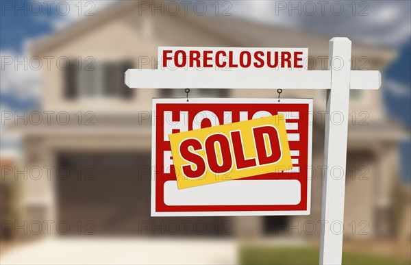 Sold foreclosure home for sale sign and house with dramatic sky background