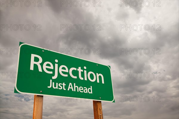 Rejection just ahead green road sign with dramatic storm clouds and sky