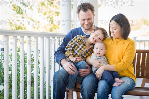 Young mixed-race chinese and caucasian family portrait on their front porch