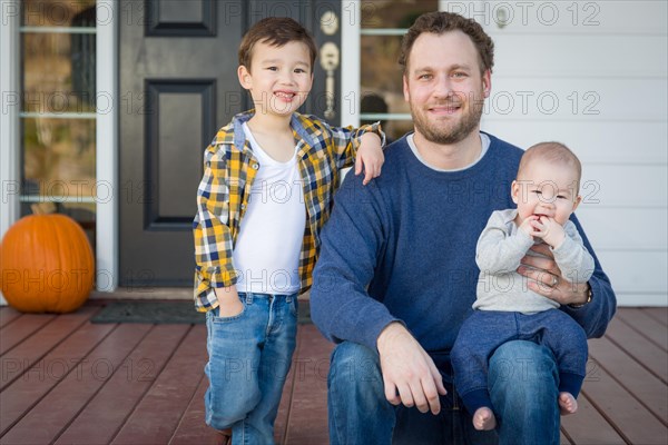 Young mixed-race father and sons on front porch
