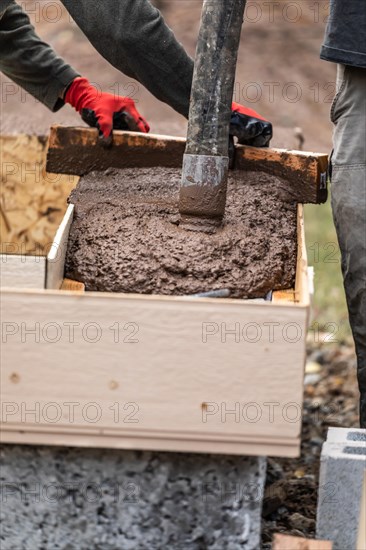 Construction workers pouring and leveling wet cement into wood framing