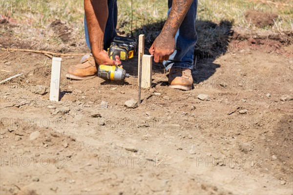 Worker installing stakes and lumber guides at construction site