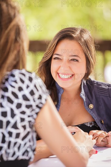 Two mixed-race girlfriends having A conversation at an outoor patio table