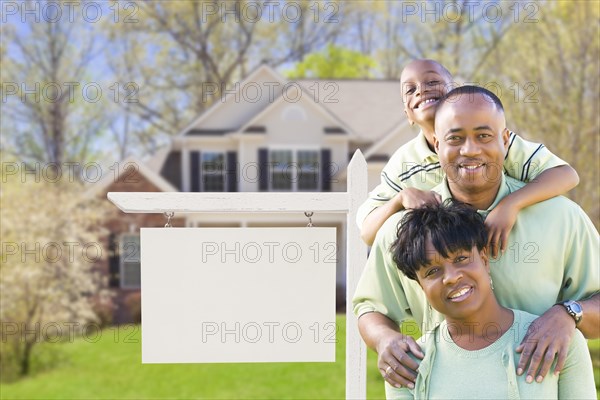 African american family in front of blank real estate sign and new house