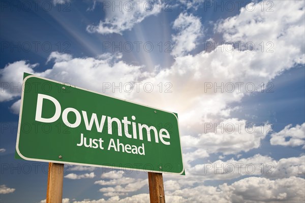 Downtime just ahead green road sign with dramatic clouds and sky