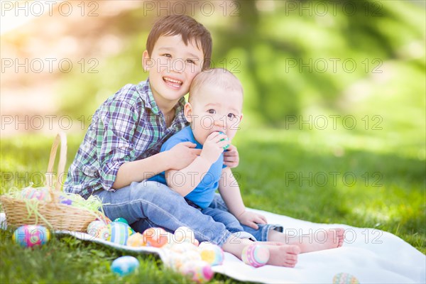 mixed-race chinese and caucasian boys outside in park playing with easter eggs