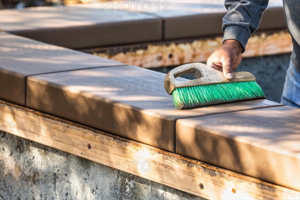 Construction worker using brush on wet cement forming coping around new pool