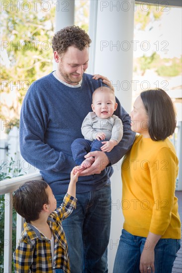 Young mixed-race chinese and caucasian family portrait on their front porch