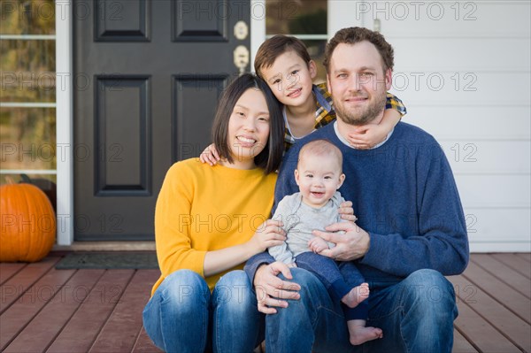 Young mixed-race chinese and caucasian family portrait on their front porch